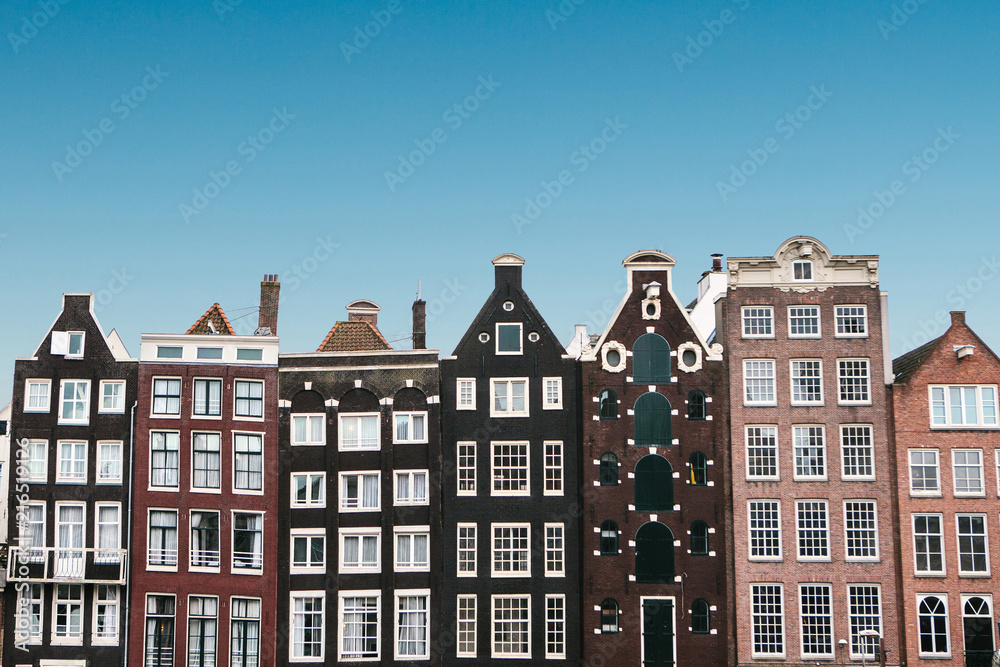 Traditional houses in Amsterdam in the Netherlands in a row against the blue sky.