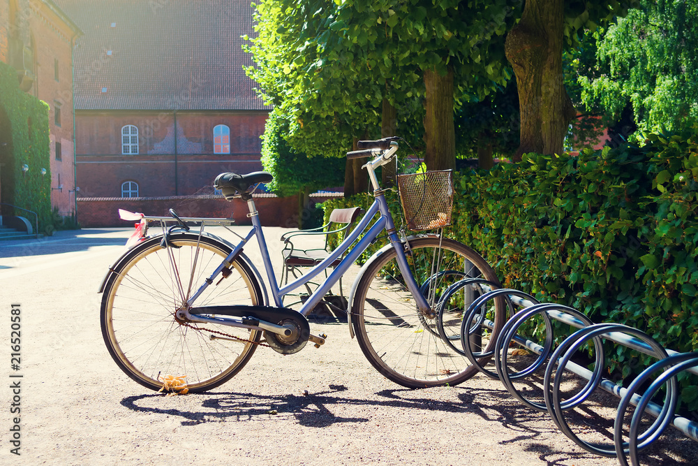 Old bicycle in the parking lot, in a beautiful garden. Summer sunny day. Transpot. Bicycles.