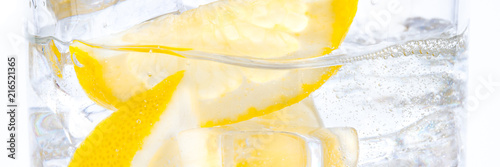 In a glass with cubes of melting ice slices of a juicy yellow lemon.
