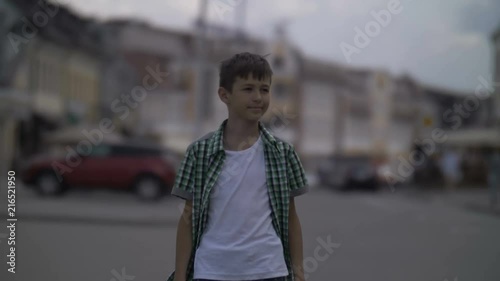happy boy walks around city center, looks around photo