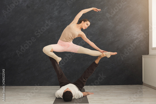 Young couple practicing acroyoga on mat together
