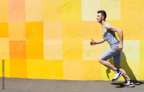 Side view of man running against bright wall