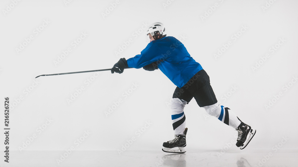 Obraz premium Portrait of Caucasian male ice hockey player in uniform performing a slap shot against white background