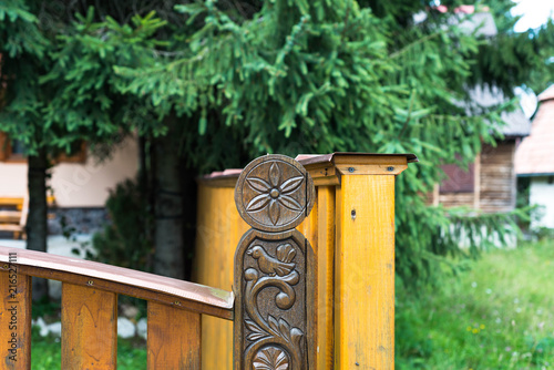 Carved sun , bird symbol on oak gate in front of residentual house. photo