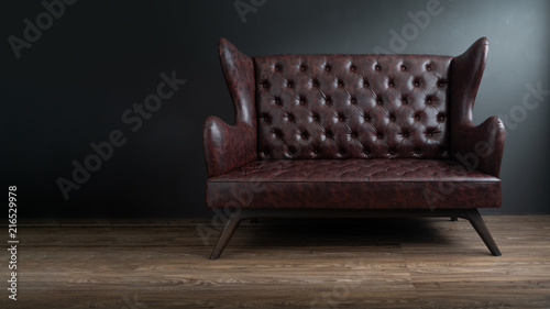 Photography Sofa of black leather standing in center on concrete floor against dark grey wall with copy space