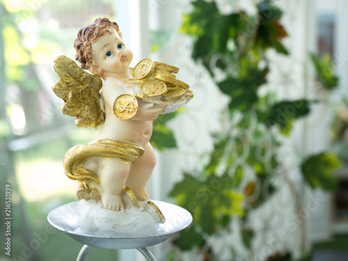Statuette of Cupid holding a lot of golden money meaning that fortune and money after marriage.