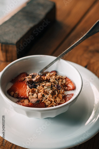 Yogurt with granola, strawberries on wooden coffee table. Hipster coffee shop. Food photography concept. Copy space