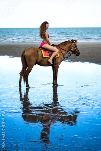 Young beautiful woman riding horse on seacoast