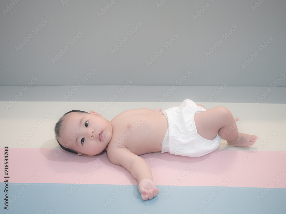Asian baby lying playing on the bed, Baby development stages of 3 month old. Asian baby lying playing on the bed, Baby development stages of 3 month old.