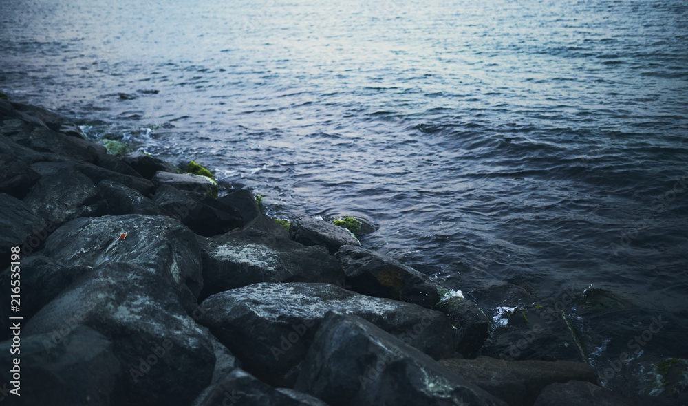 Fototapeta premium Splashing wave on Stone in sea on sunset time.