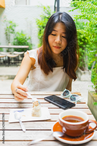 Young Asian woman enjoying with cake and coffee in the coffee shop.