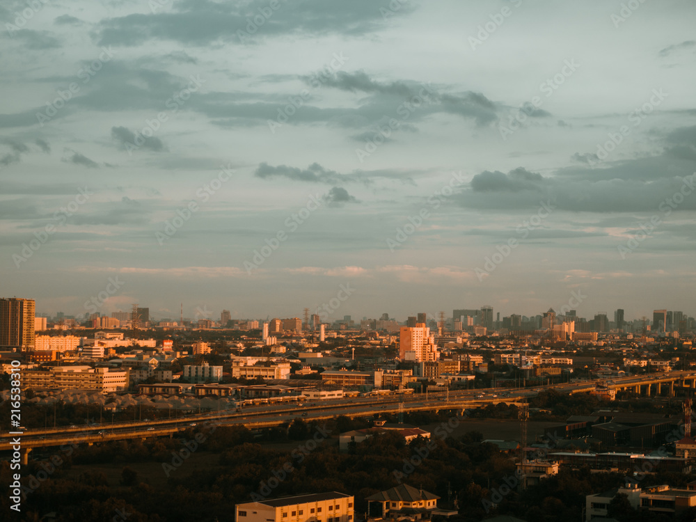 Cityscape of unknow city with thick clouds and sunset light.