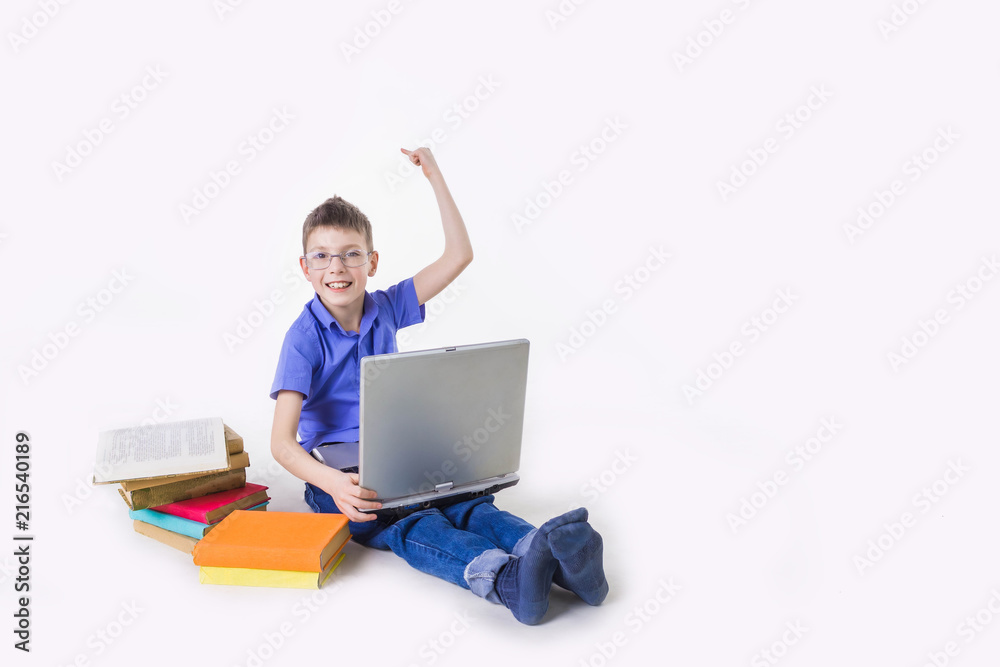 Portrait of cute schoolboy sitting with books and typing on laptop keyboard Portrait of cute schoolboy sitting with books and typing on laptop keyboard