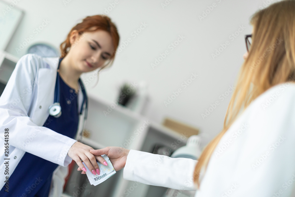 A beautiful young girl in a white robe is standing near a computer desk in the office and communicating with the interlocutor. The interlocutor shakes the girl's hand and hands her the money. A beautiful young girl in a white robe is standing near a computer desk in the office and communicating with the interlocutor. The interlocutor shakes the girl's hand and hands her the money.