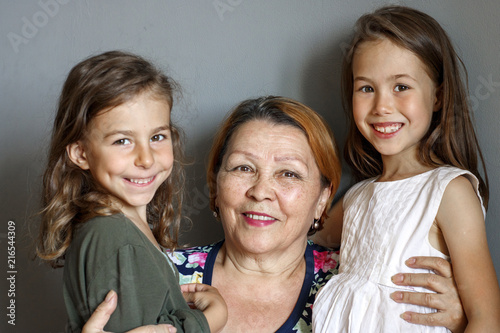 Little beautiful granddaughters kiss their beloved grandmother on both sides