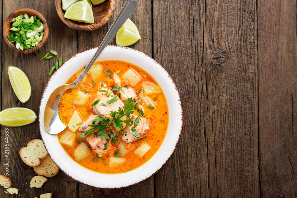 Salmon soup with cream, potatoes, carrots and parsley on gray background. top view. Salmon soup with cream, potatoes, carrots and parsley on gray background. top view.