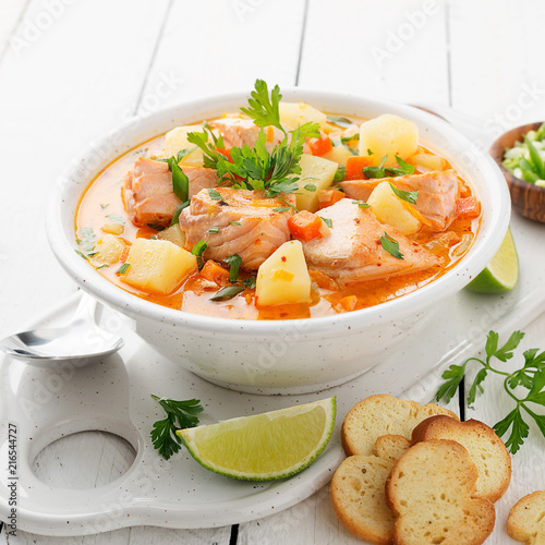 Salmon soup with cream, potatoes, carrots and parsley on white background.