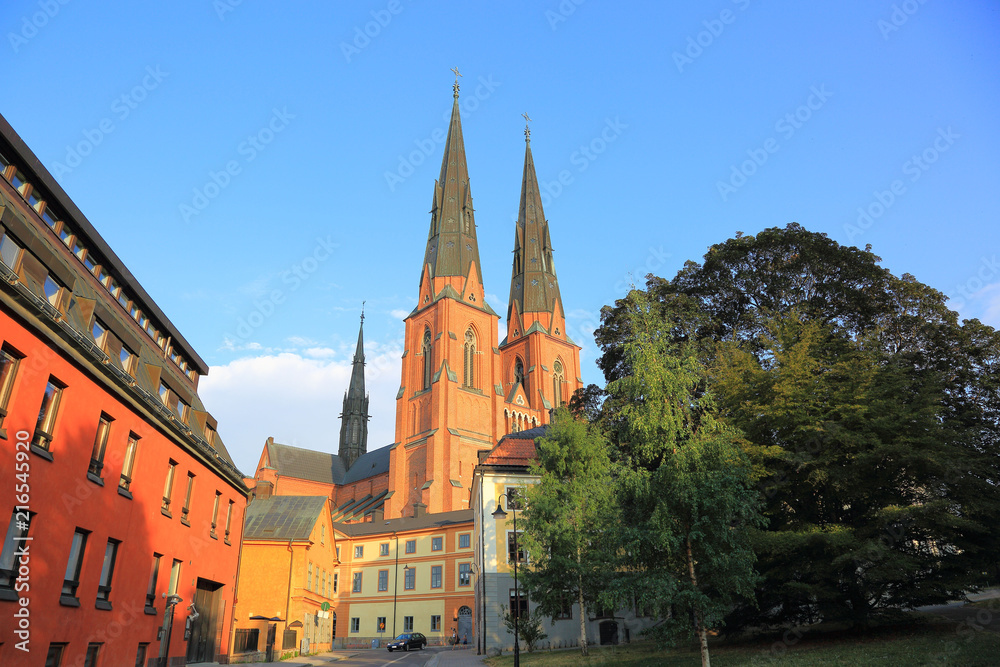 Amazing view on old historical cathedral  with green trees on front and blue sky on background. Uppsala, Sweden, Europe. Beautiful backgrounds