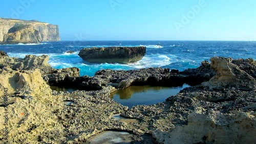 The stormy waves with white splashes cover the rocky coast of San Lawrenz, neighboring with Azure Window (Dwejra) site, Gozo, Malta. photo