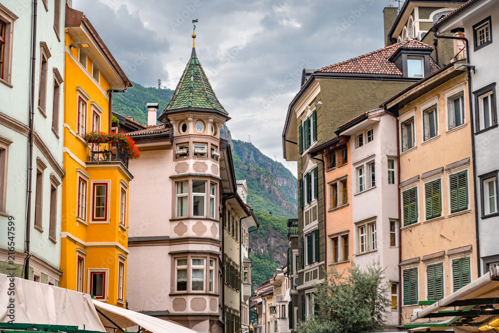 Colorful historic buildings in the city center of Bolzano with high mountains in the background