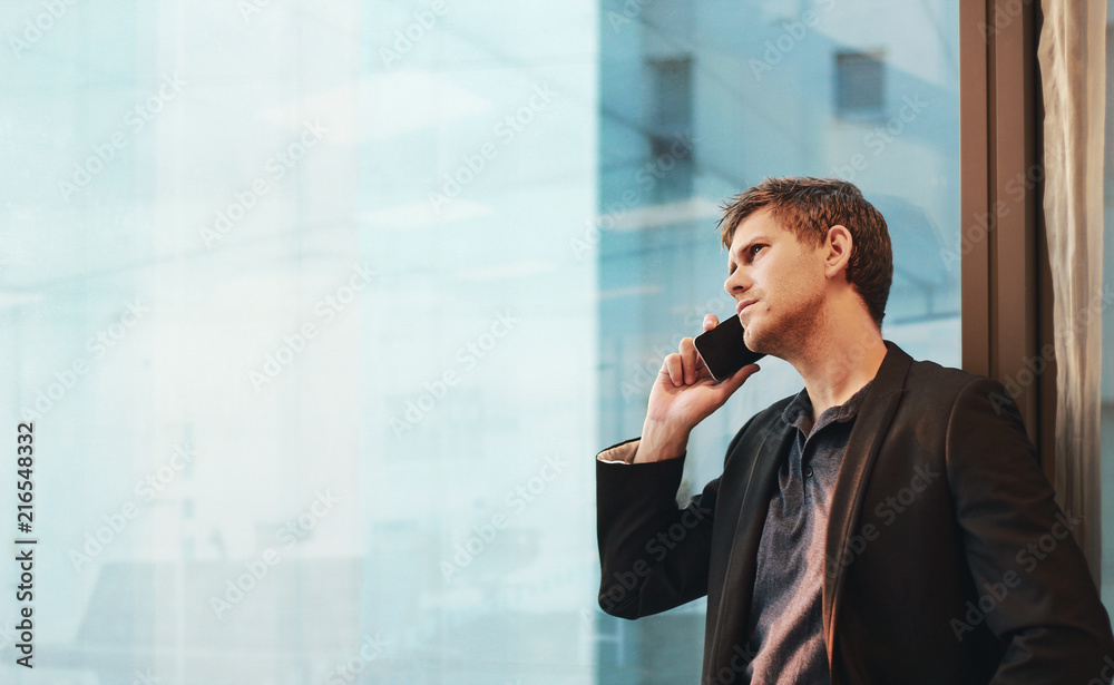 Businessman on the phone standing at the window Businessman on the phone standing at the window
