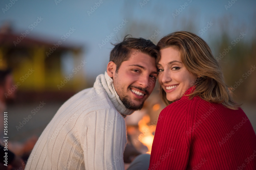 Fototapeta premium Couple enjoying with friends at sunset on the beach