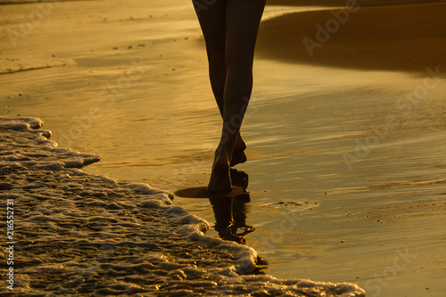 Closeup of woman's feet walking on the beach during a golden sunset. © Angelov