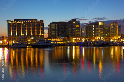 Residential buildings near waterfront and marina at dawn in Washington DC. The Wharf district buildings and their colorful reflection in Potomac River.