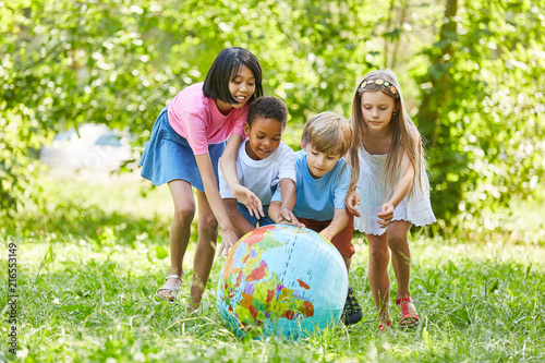 Multikulturelle Gruppe Kinder rollt Weltkugel photo