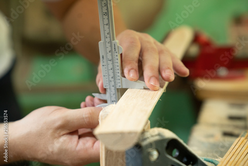 Mann kontrolliert das Maß des Holzwerkstücks in einer Werkstatt