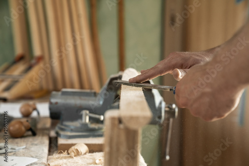 Mann arbeitet mit einer Raspel auf Holzwerkstück in einer Werkstatt