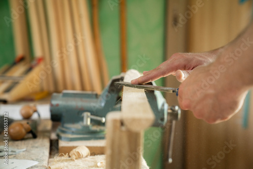 Mann arbeitet mit einer Raspel auf Holzwerkstück in einer Werkstatt