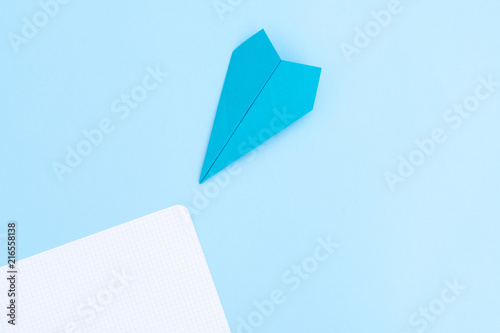 Back to school minimal flat lay styled scene with paper plane on blue background