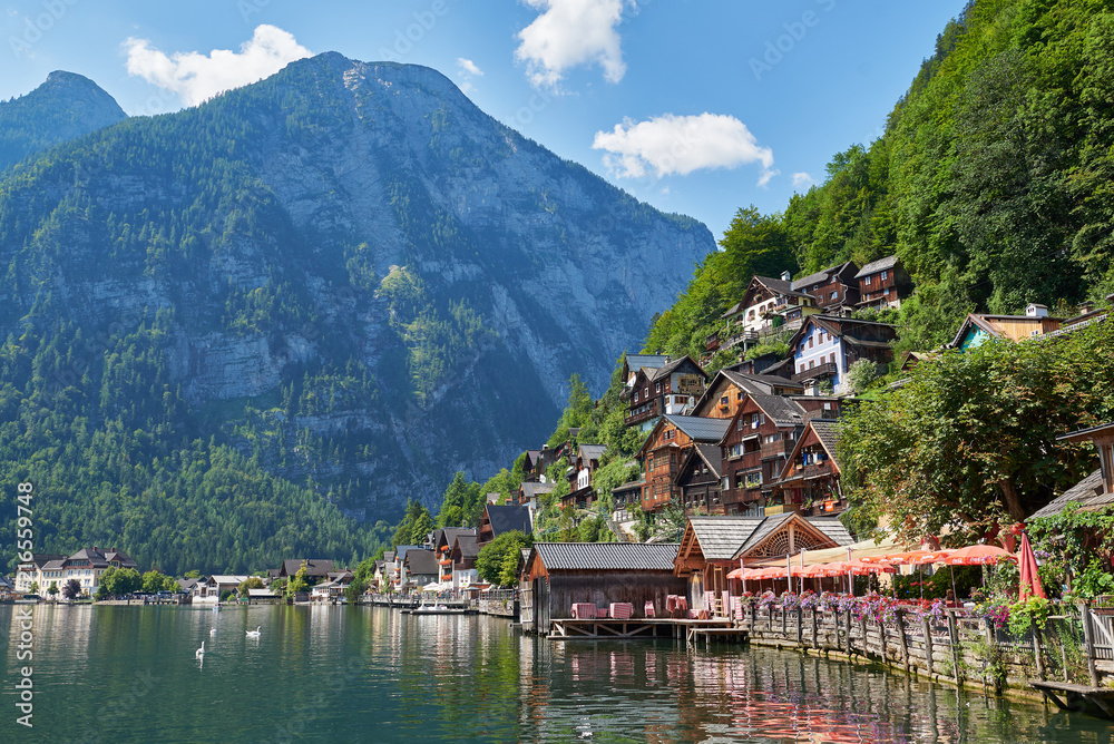 Classic postcard view of famous Hallstatt lakeside town reflecting in Hallstattersee lake in the Austrian Alps in scenic beautiful sunny day in summer, Salzkammergut region, Austria. Neutral colors.