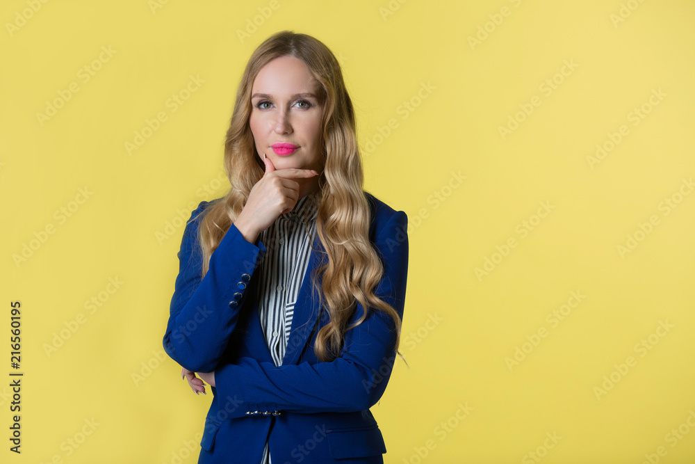 beautiful young woman with flowing hair in a blue jacket on a yellow background beautiful young woman with flowing hair in a blue jacket on a yellow background