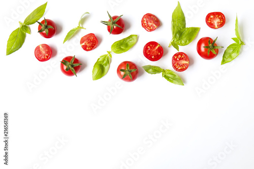 Bunch of beautiful juicy organic red cherry tomatoes, green basil leaves on white background. Shiny polished glossy vegetables. Clean eating concept. Vegetarian diet. Copy space, flat lay, top view.