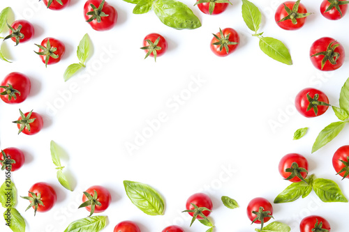 Bunch of beautiful juicy organic red cherry tomatoes, green basil leaves on white background. Shiny polished glossy vegetables. Clean eating concept. Vegetarian diet. Copy space, flat lay, top view.