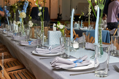 The chic restaurant is ready to receive guests. Blurred people in the background. Everything is ready for the wedding, celebrating the birthday, christening, another celebration.