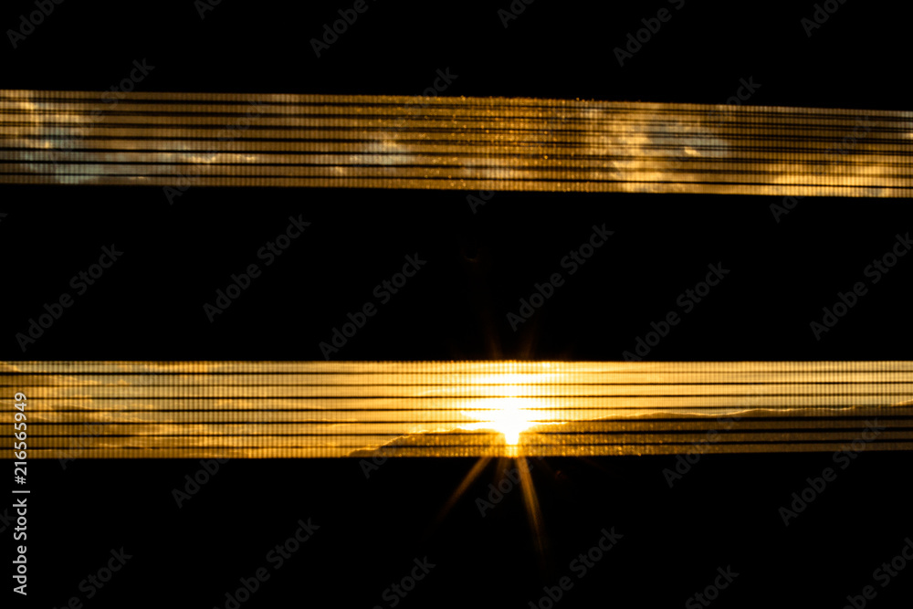 Obraz premium Czarna roleta przebija zachód słońca