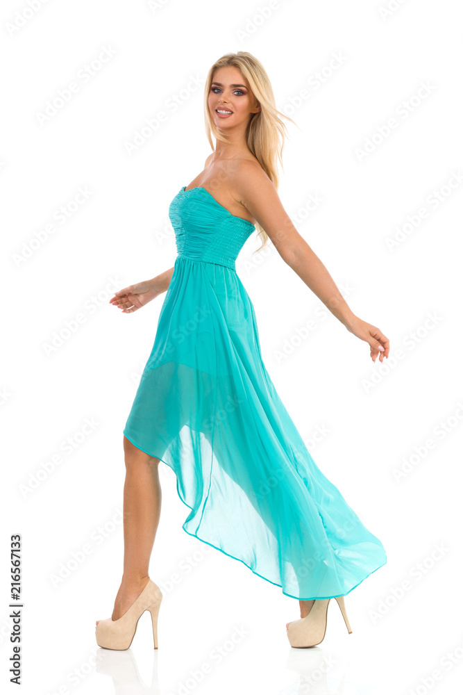 Fashion Model In Turquoise Dress Is Walking And Looking At Camera