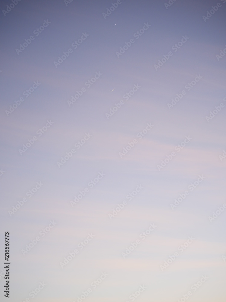 Light colored sunset sky with new moon background Light colored sunset sky with new moon background