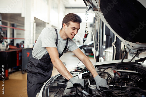 A man is checking a car engine at his work
