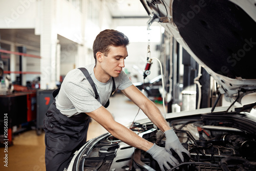 A good-loking young mechanic is reparing a vehicle at his work