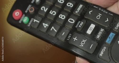 Woman turning the volume up on a television remote control