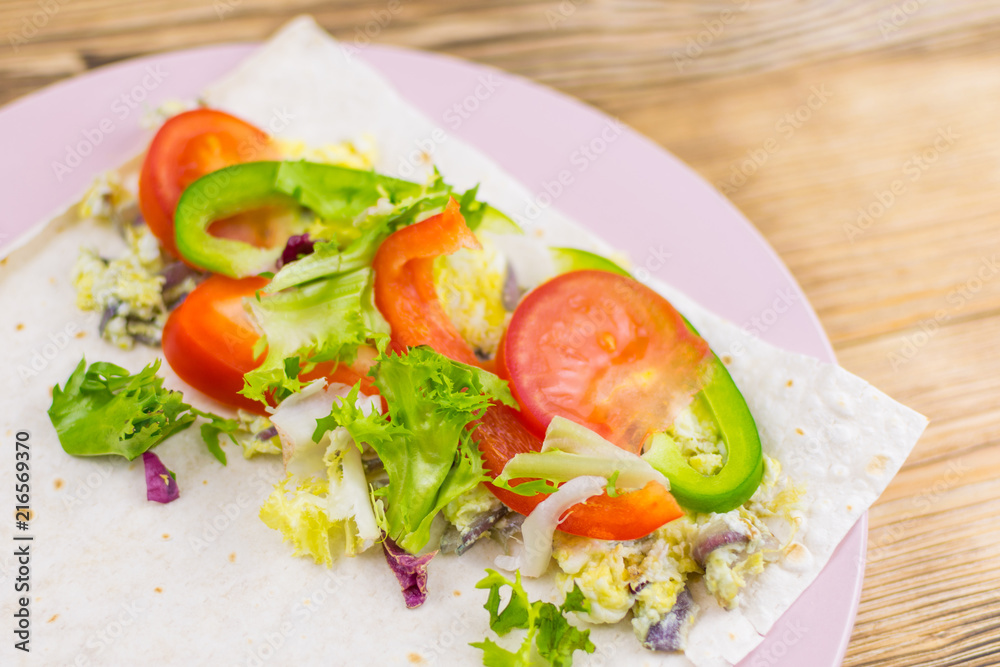 Preparation of a roll of pita bread and fresh vegetables on a wooden background. The concept of healthy eating. Preparation of a roll of pita bread and fresh vegetables on a wooden background. The concept of healthy eating.