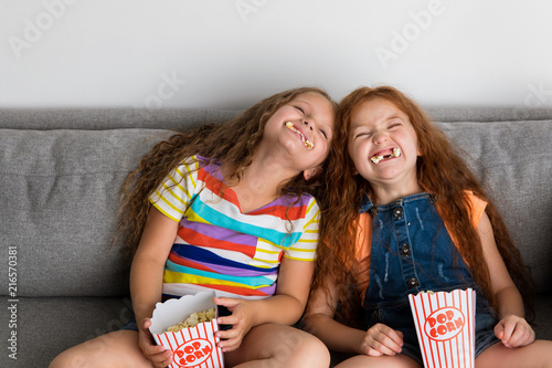 Young girls making silly faces with pop corn in their mouth