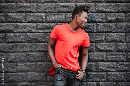 African male model standing in empty red t-shirt against brick wall