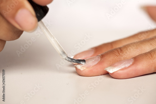 closeup of dark skinned woman polishing her finger nails on white background