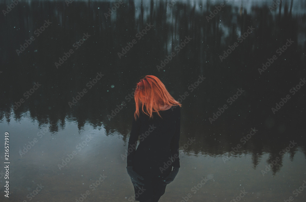 Handsome redhead girl looking down. Snowflakes falling on her hair. Splendid shady black mountain lake. Dreamy winter landscape of Carpathian mountains. Handsome redhead girl looking down. Snowflakes falling on her hair. Splendid shady black mountain lake. Dreamy winter landscape of Carpathian mountains.