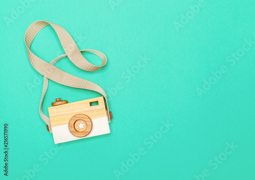 view from above on a wooden children's handmade camera on a bright colored paper background with space for text. flat lay